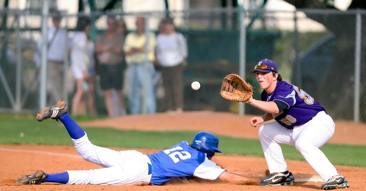 A thrilling moment in a baseball game as a runner slides into base while the fielder prepares to catch the ball.